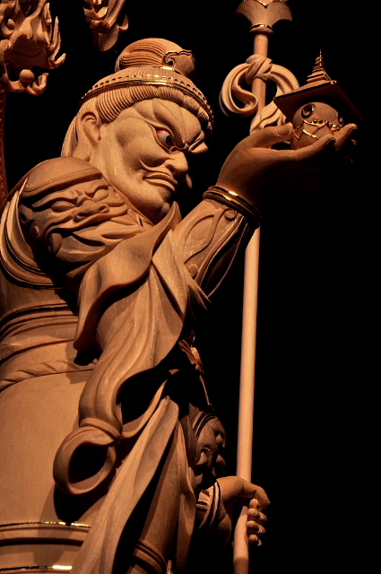 仏像彫刻原田謹刻 毘沙門天像 サンスクリット名ヴァイシュラヴァナ(Vaiśravaṇa)を写したもので多聞天とも訳す。古代インド神話中のクベラ(Kuvera,俱尾羅 ガンジス河のワニを神格化した神)が仏教にとり入れられた。拘毘羅(くびら)毘沙門と称されることもある。四天王の一尊として北方をつかさどり,また財宝富貴をも守るといわれる。形像は,甲冑を着る武神像で,一方の掌に宝塔をのせ,もう一方の手に戟または宝棒を持ち2邪鬼の上に乗る姿が一般的である。吉祥天は毘沙門天の妻である。