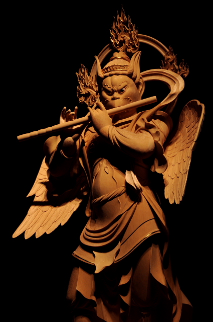 仏像彫刻原田謹刻　迦楼羅王像（かるらおうぞう） サンスクリット語のガルダの音写。 天龍八部衆の第一。 蛇（コブラ）を常食とする伝説の巨鳥ガルダが仏教に取り込まれ、仏法守護の神となった。口から金の火を吹き、赤い翼を広げると336万里にも達するとされる。 仏教において、毒蛇は雨風を起こす悪龍とされ、煩悩の象徴といわれる為、龍（毒蛇）を常食としている迦楼羅は、毒蛇から人を守り、龍蛇を喰らうように衆生の煩悩（三毒）を喰らう霊鳥として信仰されている。 不動明王背後の炎は迦楼羅の吐く炎、または迦楼羅そのものの姿であるとされ「迦楼羅焔」（かるらえん）と呼ばれる。