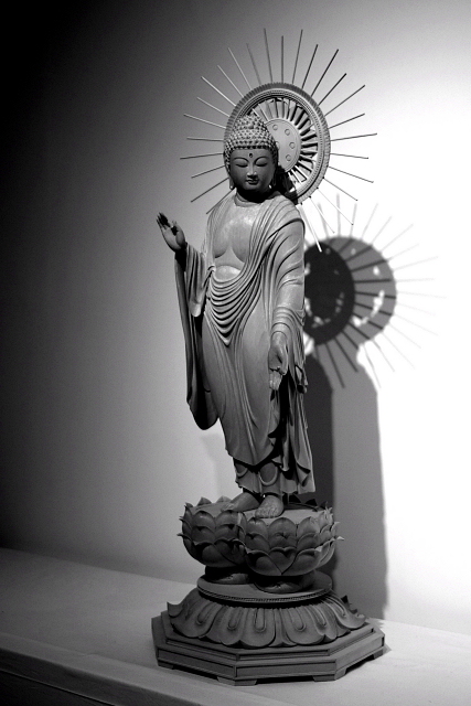 仏像彫刻原田謹刻 見返り阿弥陀像(みかえりあみだぞう) 【見返り阿弥陀】 京都市左京区にある通称永観堂(えいかんどう)の名で知られる禅林寺の本尊阿弥陀如来立像は、顔を左に曲げた特異な姿の像である。この像については次のような伝承がある。永保2年(1082年)、当時50歳の永観(ようかん)が日課の念仏を唱えつつ、阿弥陀如来の周囲を行道していたところ、阿弥陀如来が須弥壇から下り、永観と一緒に行道を始めた。驚いた永観が歩みを止めると、阿弥陀如来は振り返って一言、「永観遅し」と言ったという。本寺の阿弥陀如来像はそれ以来首の向きが元に戻らず、そのままの姿で安置されているのだという。 ◆上記の伝承に基づき、御寺院様の御用命で謹刻させて頂きました。