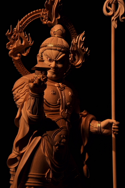 仏像彫刻原田謹刻 　毘沙門天像 サンスクリット名Vaiśravaṇaを写したもので多聞天とも訳す。古代インド神話中のクベラ(Kuvera，俱尾羅)が仏教にとり入れられた。四天王の一尊として北方をつかさどり，また財宝富貴をも守るといわれる。密教においては十二天の一尊であり，やはり北方に位置される。