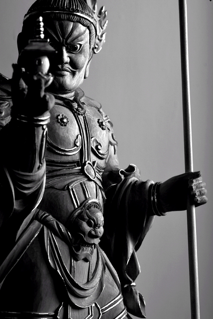 仏像彫刻原田謹刻　毘沙門天立像（びしゃもんてんりゅうぞう） 【毘沙門天】 サンスクリット名ヴァイシュラヴァナを音写したもので多聞天とも訳す。古代インド神話中のクベーラ(地下に埋蔵されている財宝の守護神であり、北方の守護神とされる。)が仏教にとり入れられた。四天王の一尊として北方をつかさどり，また財宝富貴をも守るといわれる。形像は，甲冑を着る武神像で，掌上に宝塔をのせ，もう一方の手に宝棒または鉾を執り、邪鬼の上に乗る姿が一般的である。仏教では、吉祥天の夫とされる。四天王中最強で財宝の神として独立して信仰されている。